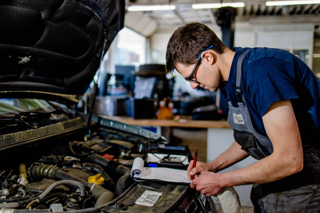 Mechaniker arbeitet an der offenen Motorhaube eines Autos