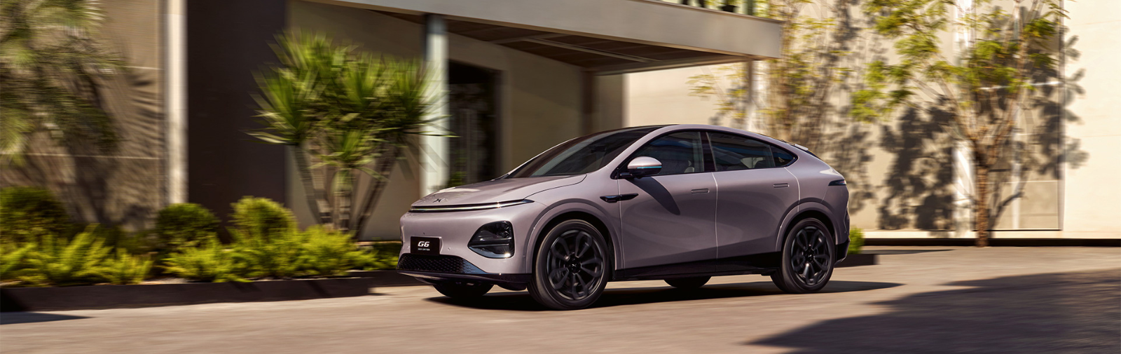XPENG G6 - Elektro SUV erhältlich bei Vogl+Co - steht, in Seitenansicht, vor einem modernen Haus.
