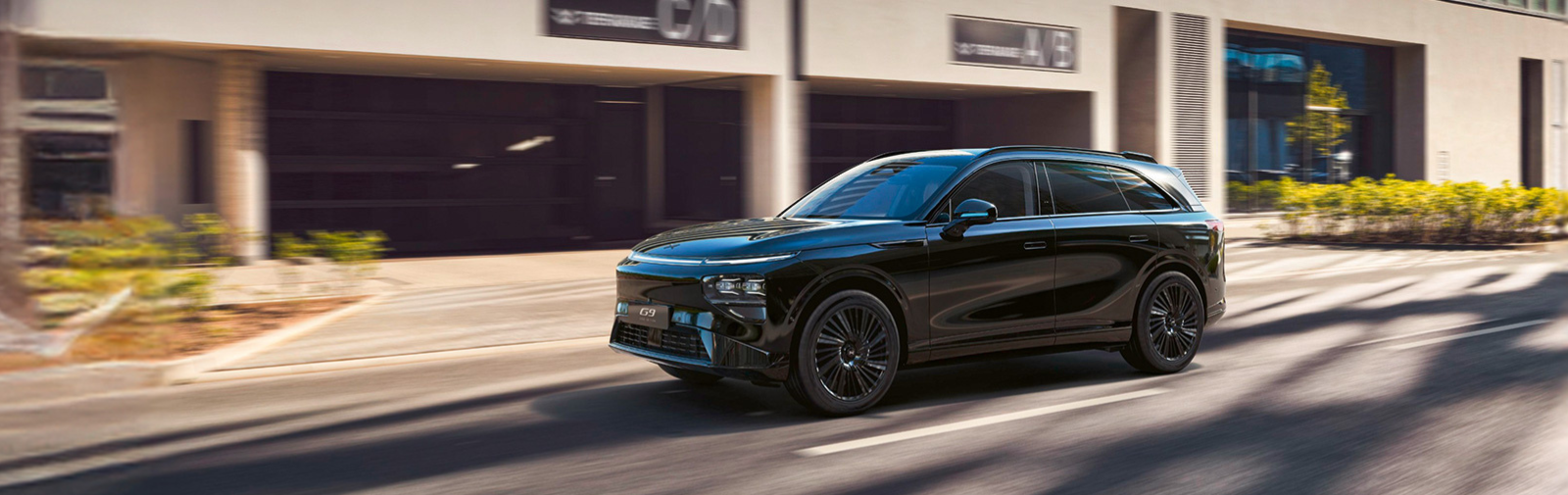 XPENG G9 - ein eleganter Elektro SUV erhältlich bei Vogl+Co - fährt auf einer sonnigen Straße.